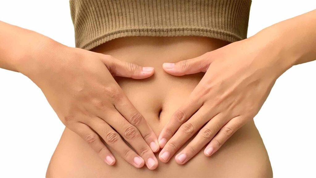 Eine Frau berührt ihren Bauch mit ihren Händen. Es steht für Darmgesundheit.
